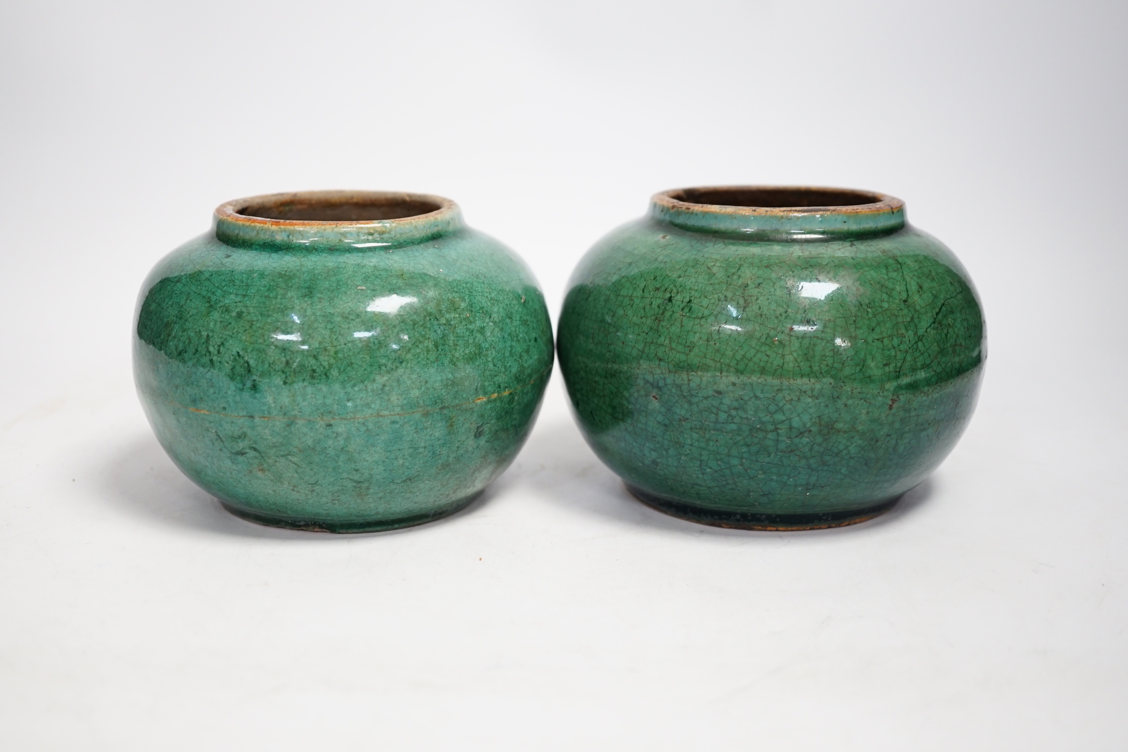 A pair of Chinese pottery monochrome green glazed jars, 10cm high